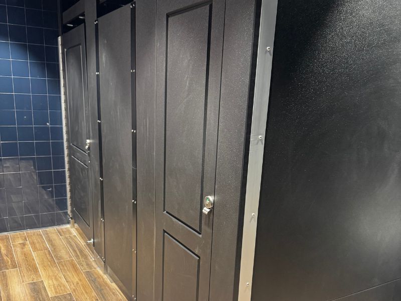 black-phenolic-toilet-partitions-restroom-installation-jacksonville-fl - Holman, Inc. Black phenolic toilet partitions with textured matte finish in a commercial restroom